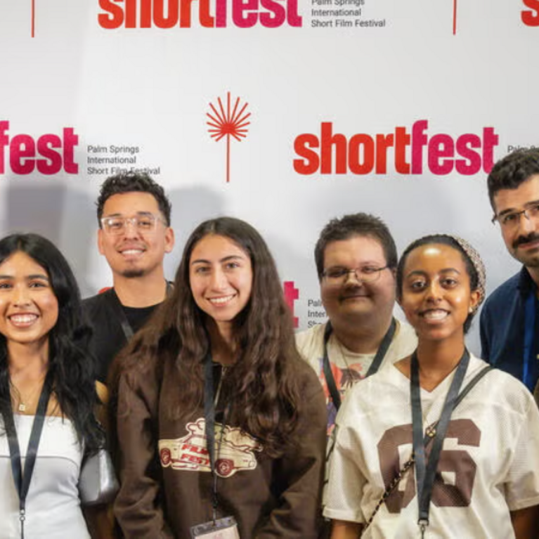 Students and faculty posing in front of a Shortfest step and repeat