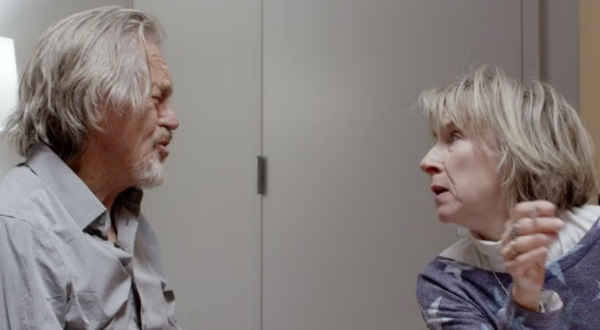 Miles Anderson and Bella Merlin staring at each other in conversation with an office background